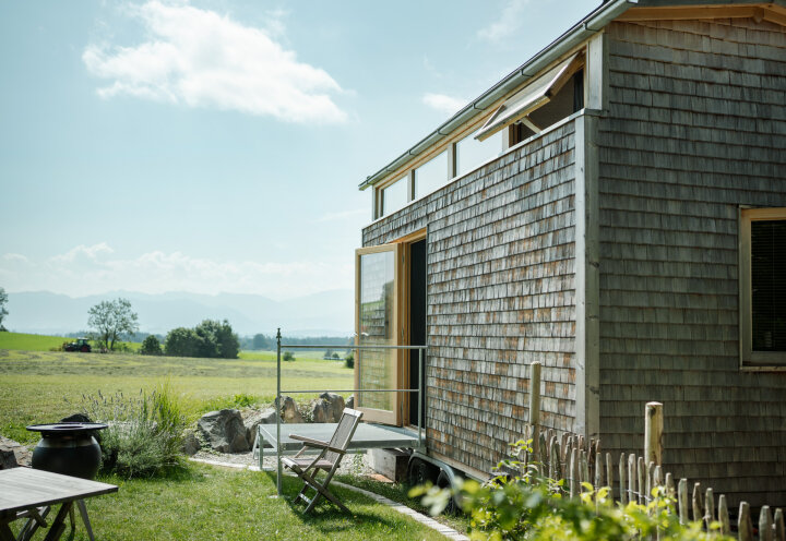 Tiny House mit Holzschindeln vor idyllischer Landschaft